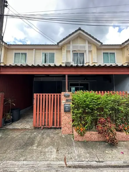 Charming two-story house with brick fence and lush greenery in a serene neighborhood.
