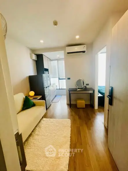 Modern apartment interior with cozy living room and stylish kitchen area, featuring wooden flooring and bright lighting.