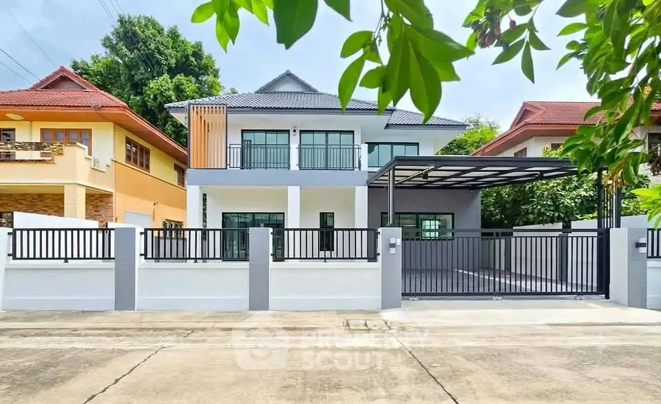 Modern two-story house with gated driveway and lush greenery