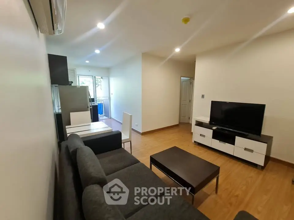 Modern living room with sleek furniture and wooden flooring, featuring a cozy ambiance and natural light.
