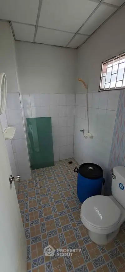 Compact bathroom with tiled floor and basic fixtures, ideal for budget-friendly living spaces.