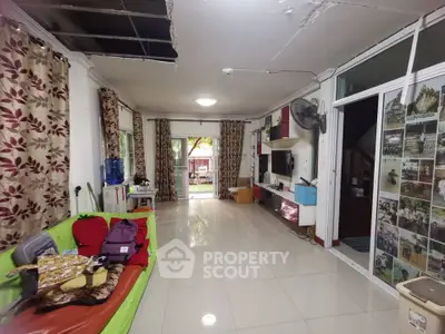 Spacious living room with tiled floor and large windows, featuring a vibrant sofa and decorative curtains.