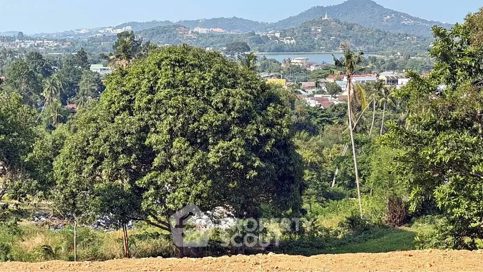 Scenic land plot with lush greenery and mountain views, ideal for development.