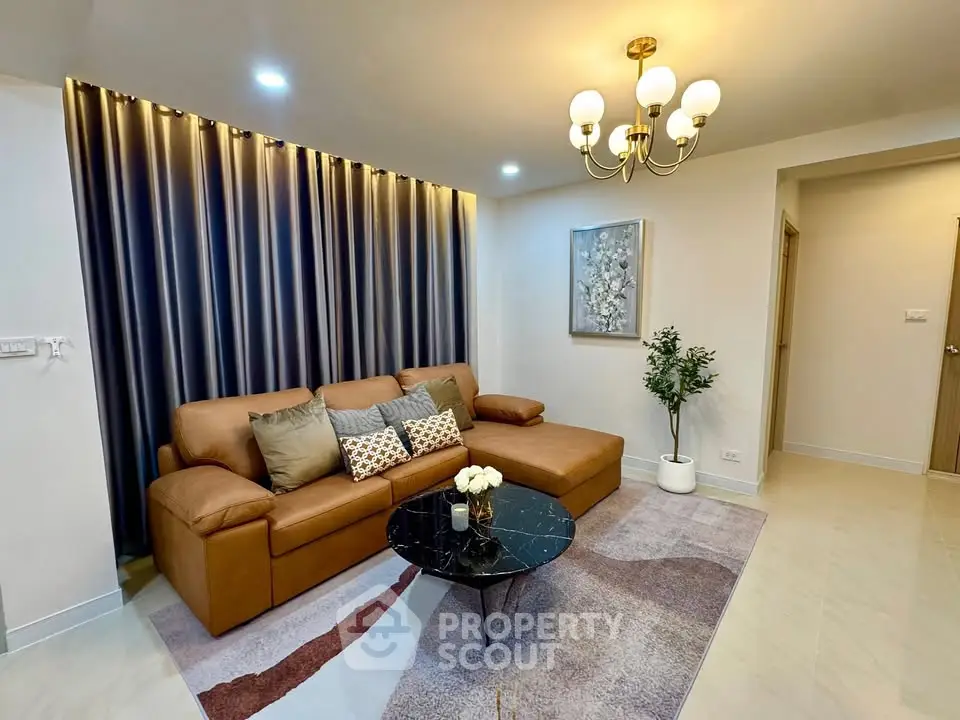 Elegant living room with modern decor, featuring a stylish brown sofa, chic chandelier, and artistic wall accents.