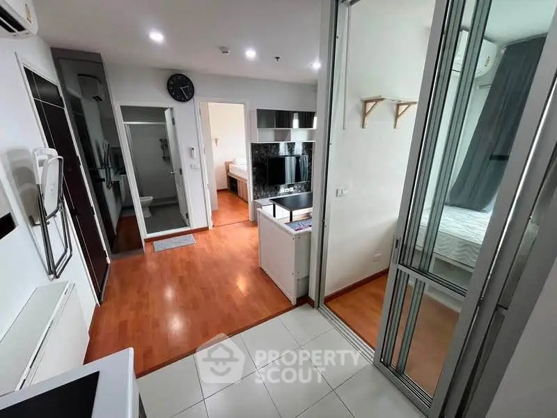 Modern apartment interior with open layout, featuring a kitchen and bedroom with sleek design.