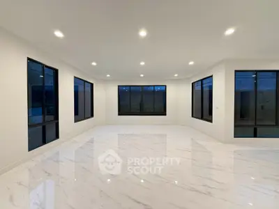 Spacious modern living room with large windows and marble flooring