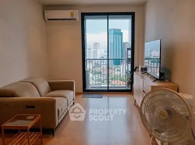 Modern living room with city view, featuring cozy sofa and sleek TV setup.