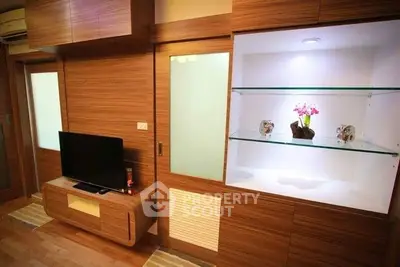 Modern living room with sleek wooden furniture and built-in display shelves.