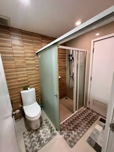 Modern bathroom with glass shower and wooden accent wall