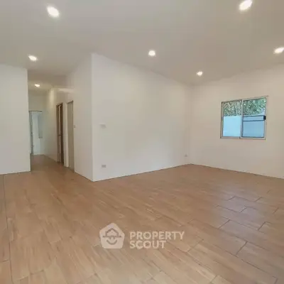 Spacious empty room with wooden flooring and recessed lighting