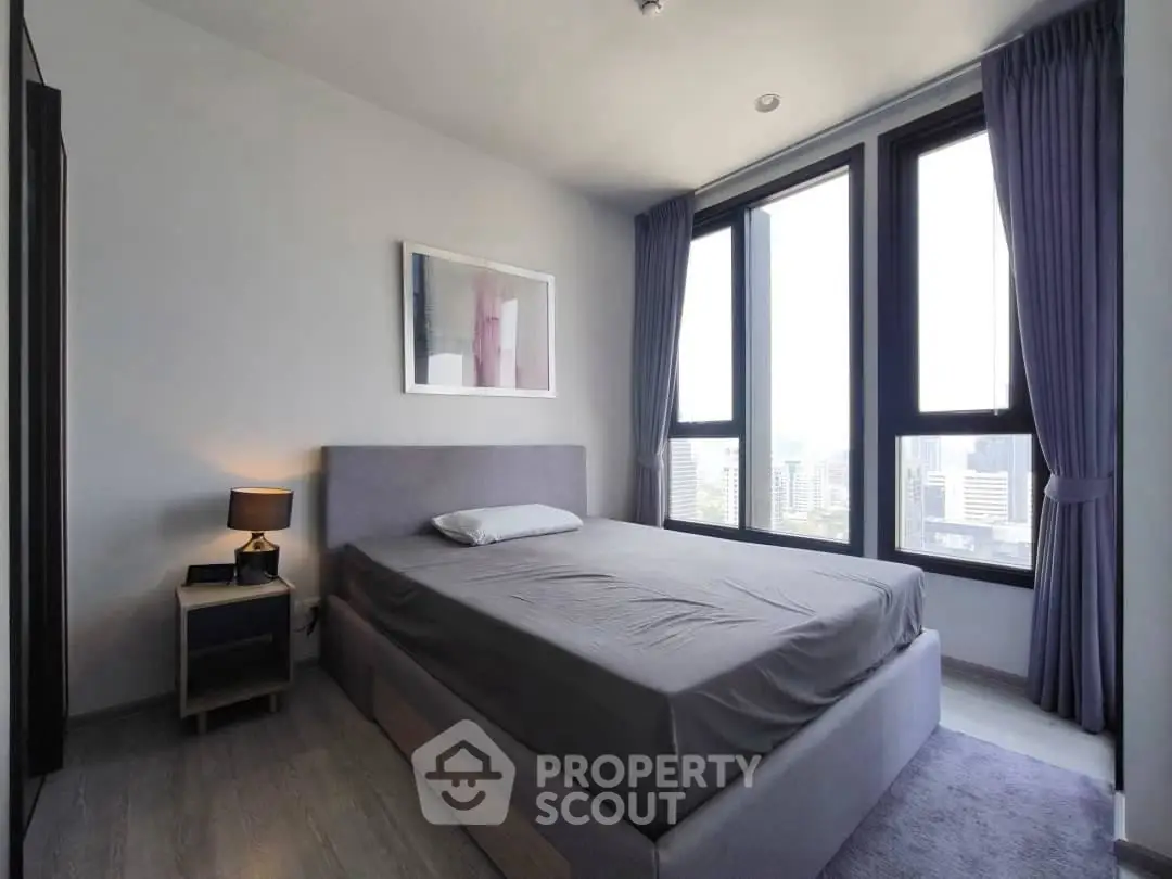 Modern bedroom with large windows and city view, featuring a stylish bed and elegant decor.