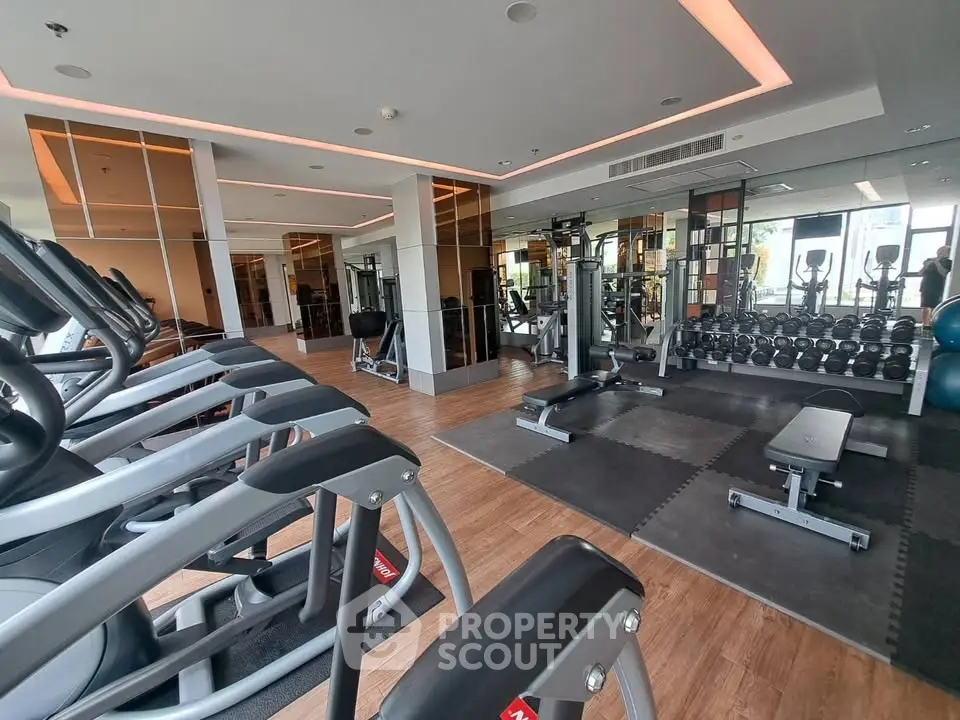 Modern gym with state-of-the-art equipment and mirrored walls in luxury apartment building.