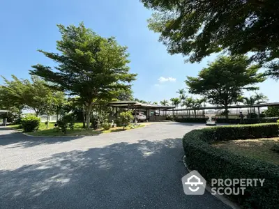 Spacious garden entrance with lush greenery and clear blue sky, perfect for serene living.