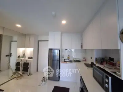 Modern kitchen with sleek white cabinets and stainless steel appliances in a cozy apartment.