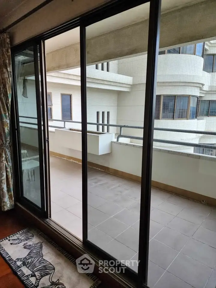 Spacious balcony with sliding glass doors and modern building view