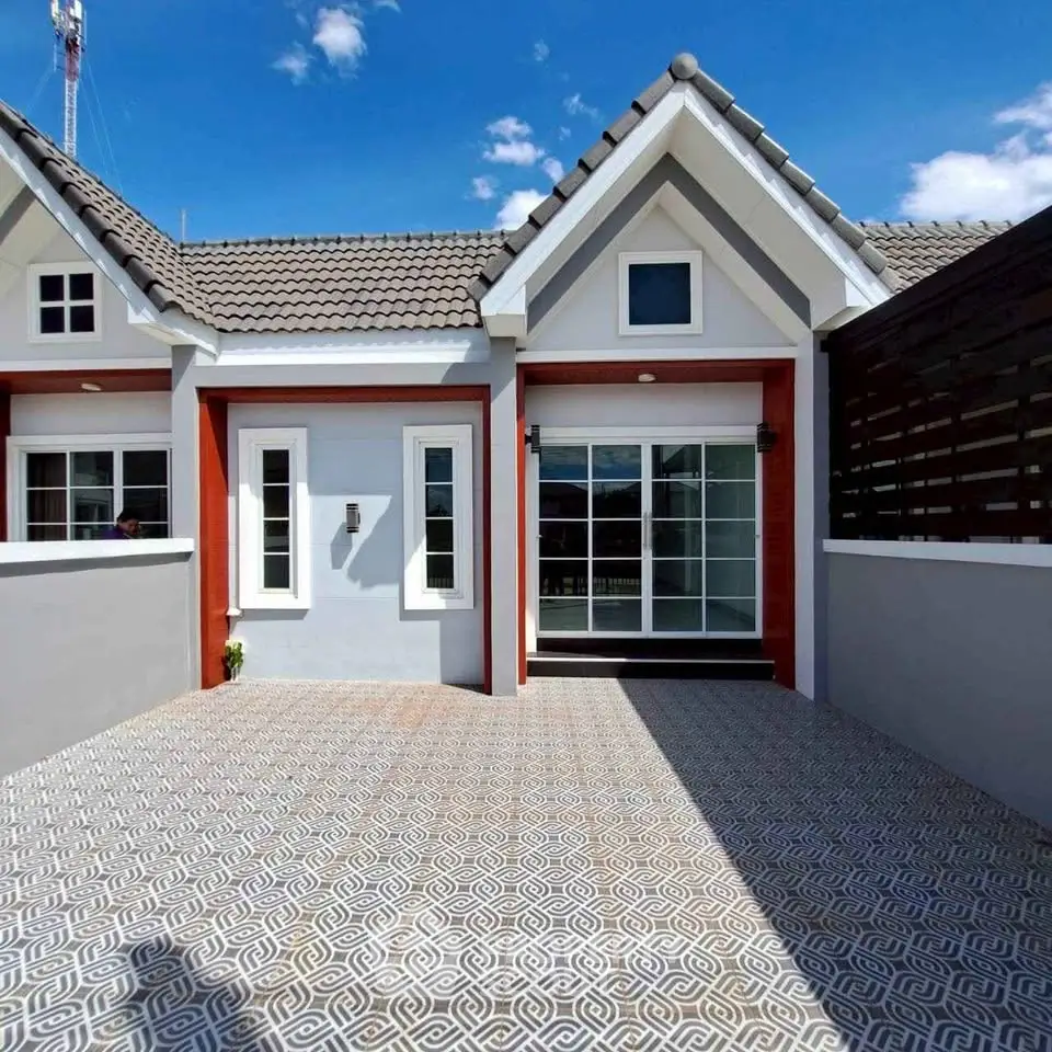 Charming modern house exterior with tiled patio and gable roof under clear blue sky.