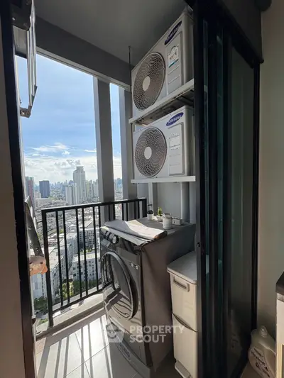 High-rise balcony with city view, featuring washing machine and air conditioning units.