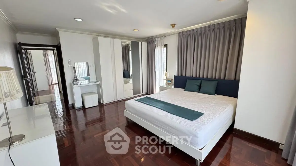 Spacious bedroom with elegant decor and hardwood floors in modern apartment.