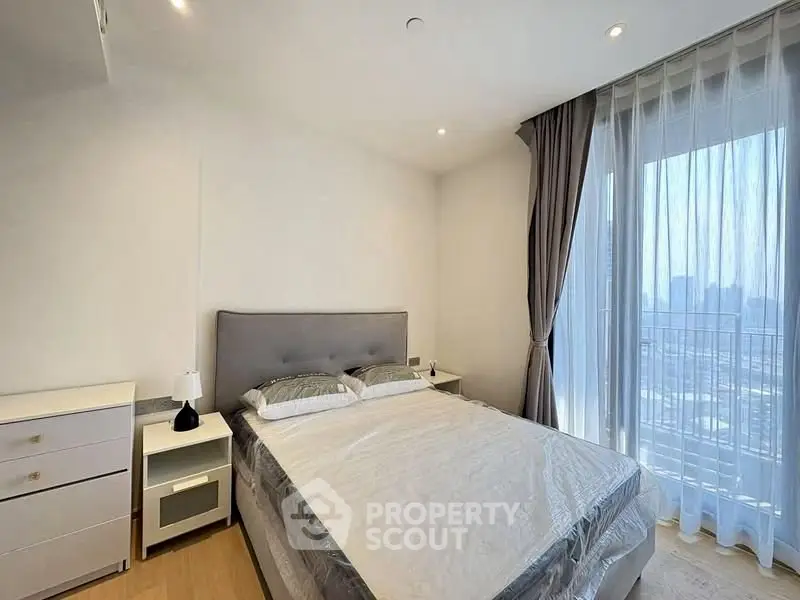 Bright and modern bedroom with large window and city view, featuring elegant decor and natural light.