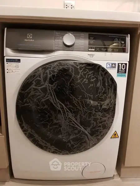 Modern Electrolux washing machine in a stylish laundry area with wooden cabinetry.