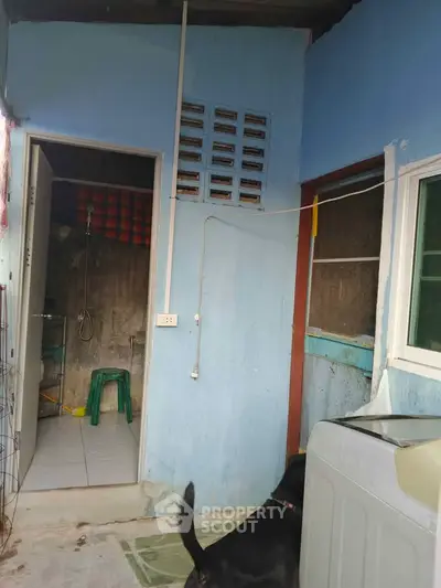 Simple laundry area with washing machine and bathroom access in a modest home.