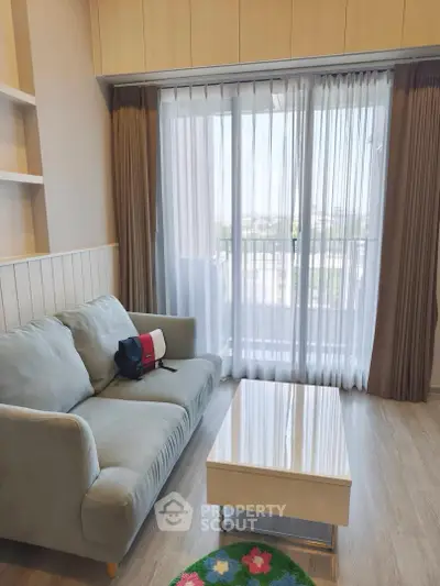 Charming living room with cozy sofa and bright natural light from large window.
