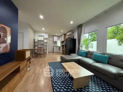 Spacious modern living room with open kitchen, featuring stylish decor and natural light.