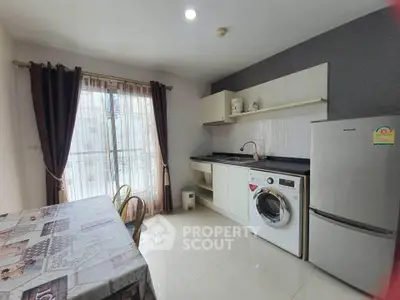 Modern kitchen with washing machine and fridge, featuring open layout and dining area.