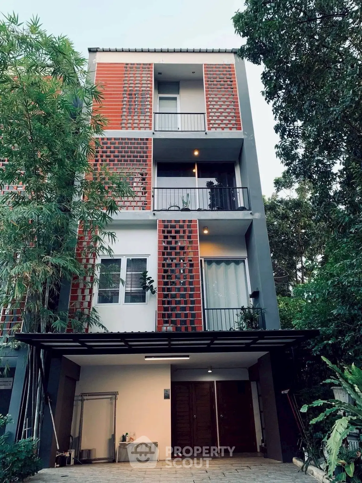 Modern multi-story building with unique brick facade and lush greenery