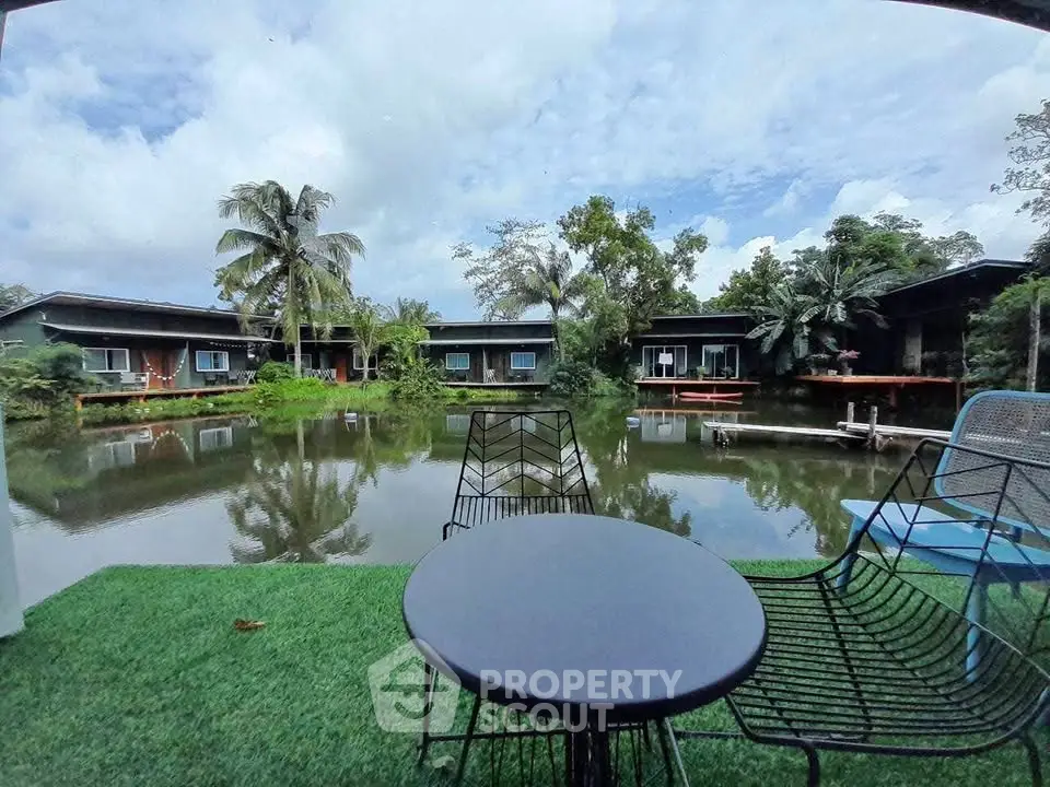 Scenic view of modern lakeside cabins with lush greenery and tranquil water reflections.