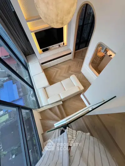 Luxurious modern living room with high ceiling and large windows offering stunning city views.