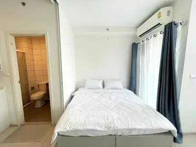 Cozy bedroom with ensuite bathroom and natural light from large window.