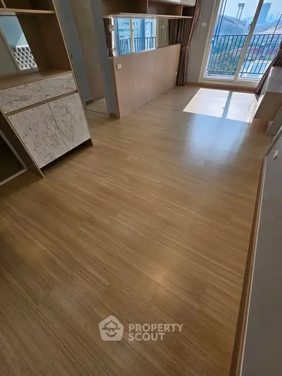 Spacious modern living room with wooden flooring and large windows for natural light.