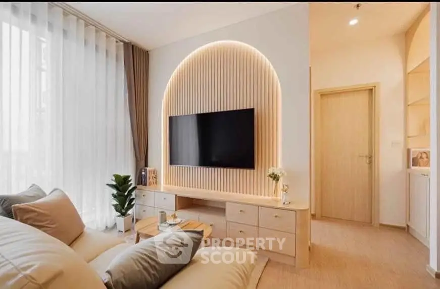 Modern living room with stylish decor and wall-mounted TV, featuring elegant lighting and cozy seating.
