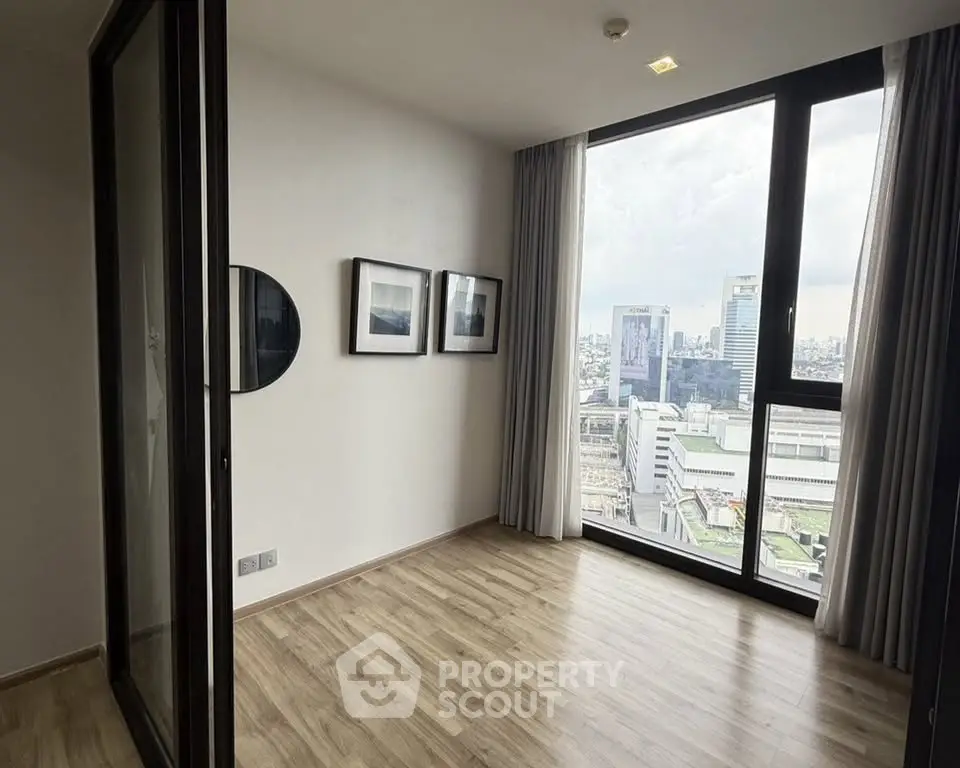 Modern apartment with large windows offering stunning city views and elegant wooden flooring.