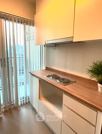 Modern kitchen with sleek cabinets and electric stove, featuring a bright balcony view.
