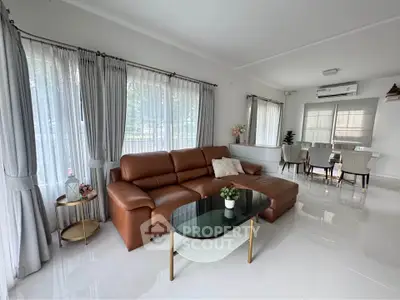 Spacious living room with elegant brown leather sofa and modern dining area.