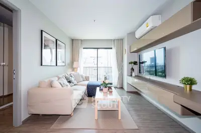 Modern living room with stylish decor and large window offering city view, featuring cozy seating and sleek entertainment unit.