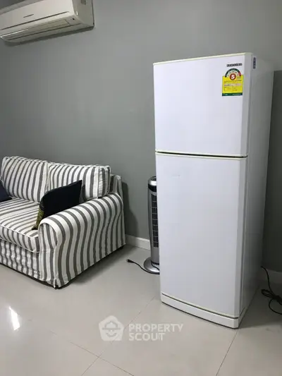 Modern living room with striped sofa and sleek white refrigerator
