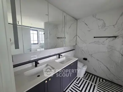 Modern bathroom with dual sinks and marble accents, featuring sleek black fixtures and geometric floor tiles.
