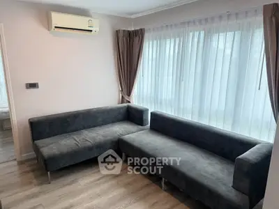 Modern living room with stylish gray sofas and large window with sheer curtains.
