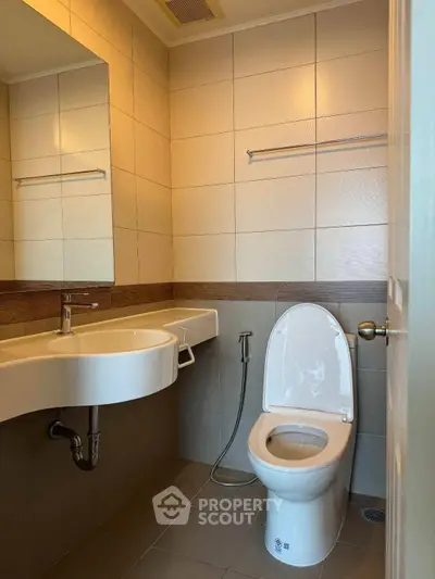 Modern bathroom with sleek fixtures and neutral tiles, featuring a wall-mounted sink and toilet.