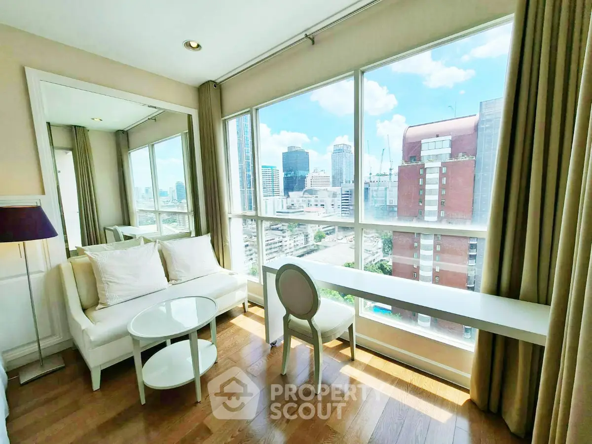 Bright living room with city view, featuring large windows, cozy seating, and elegant decor.