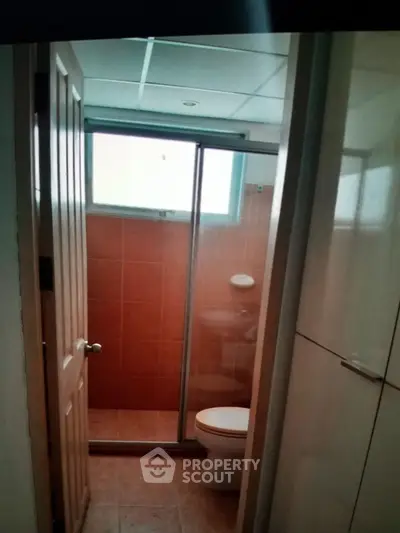 Compact bathroom with shower and tiled walls in cozy apartment