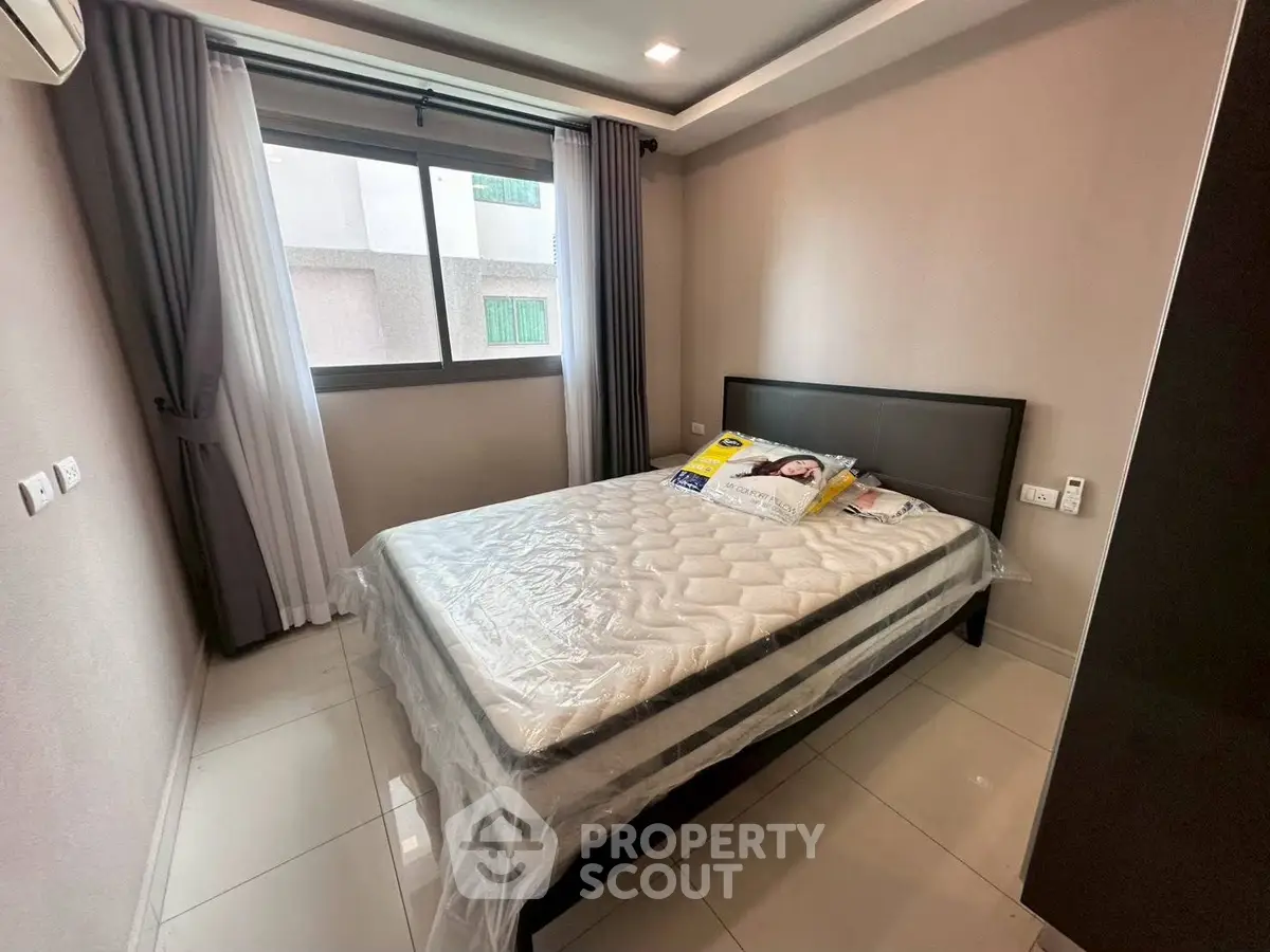 Modern bedroom with large window and stylish decor in a contemporary apartment.