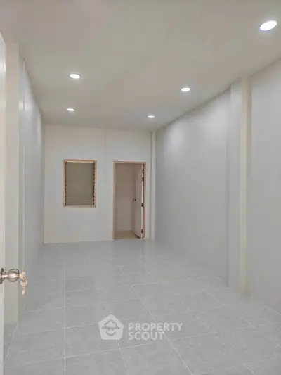 Spacious empty room with tiled flooring and recessed lighting, perfect for customization.