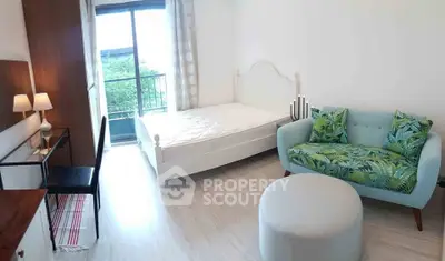 Bright bedroom with balcony access, featuring a cozy sofa and stylish decor.