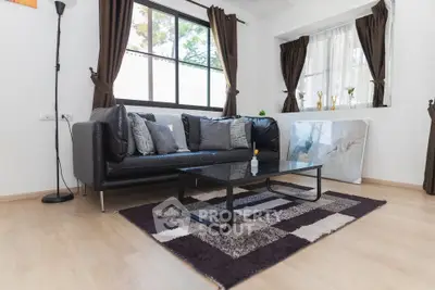 Modern living room with stylish black sofa and large window, featuring elegant decor and natural light.
