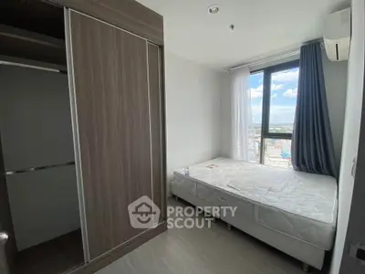 Modern bedroom with large window and city view, featuring a comfortable bed and spacious wardrobe.