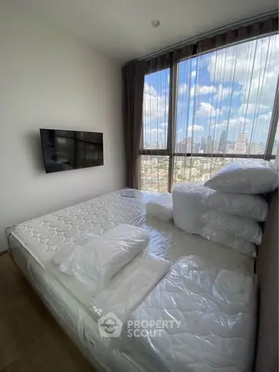 Modern bedroom with large windows offering stunning city views and a wall-mounted TV.